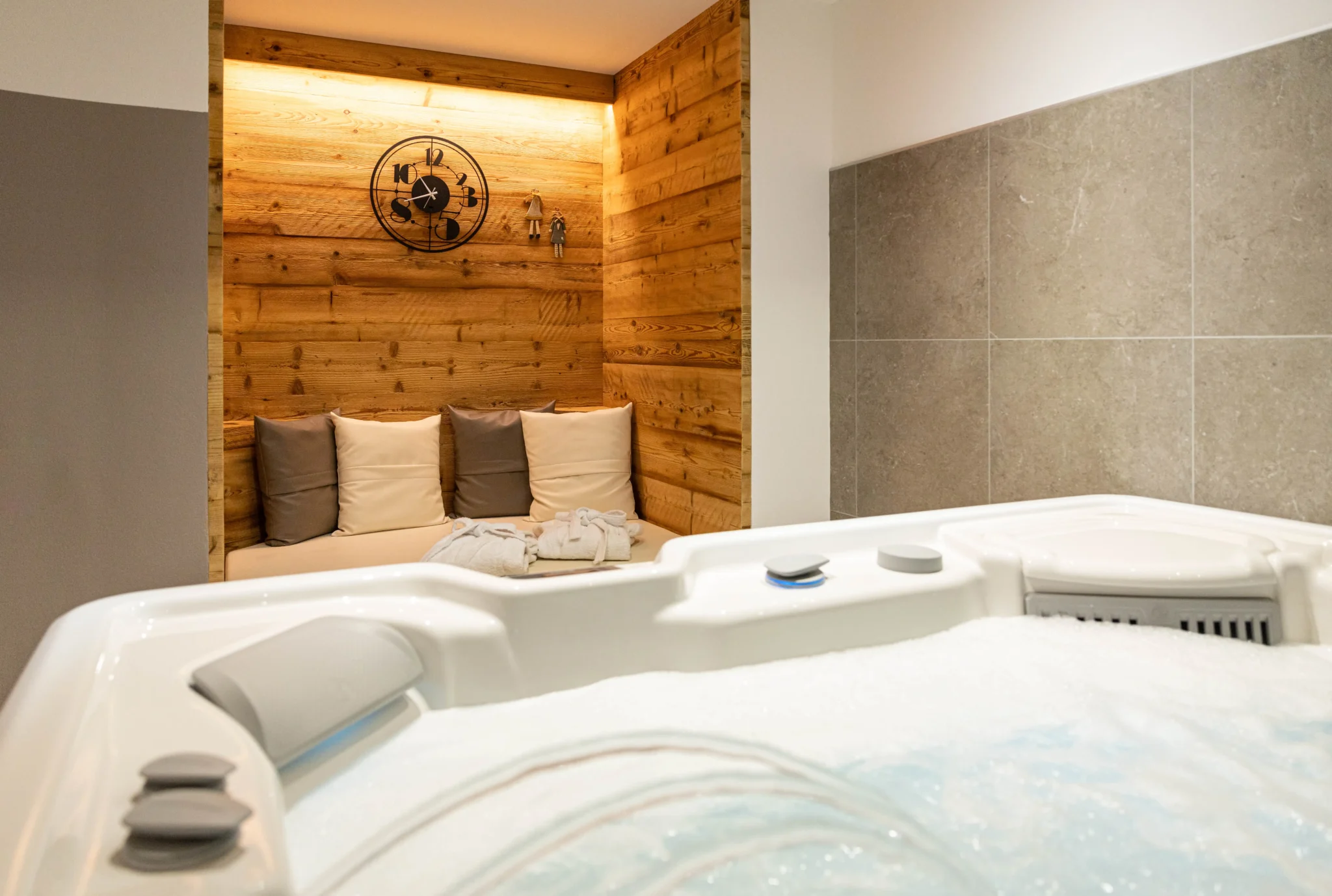 Vasca idromassaggio in un ambiente elegante con pareti in legno e divano accogliente.