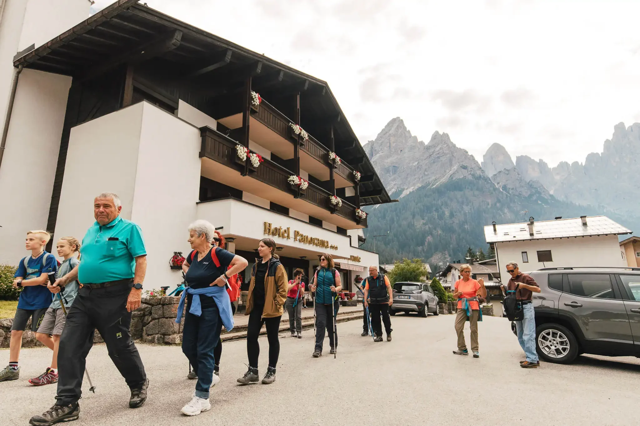 Gruppo di persone con attrezzatura da trekking davanti a un hotel nelle Dolomiti.