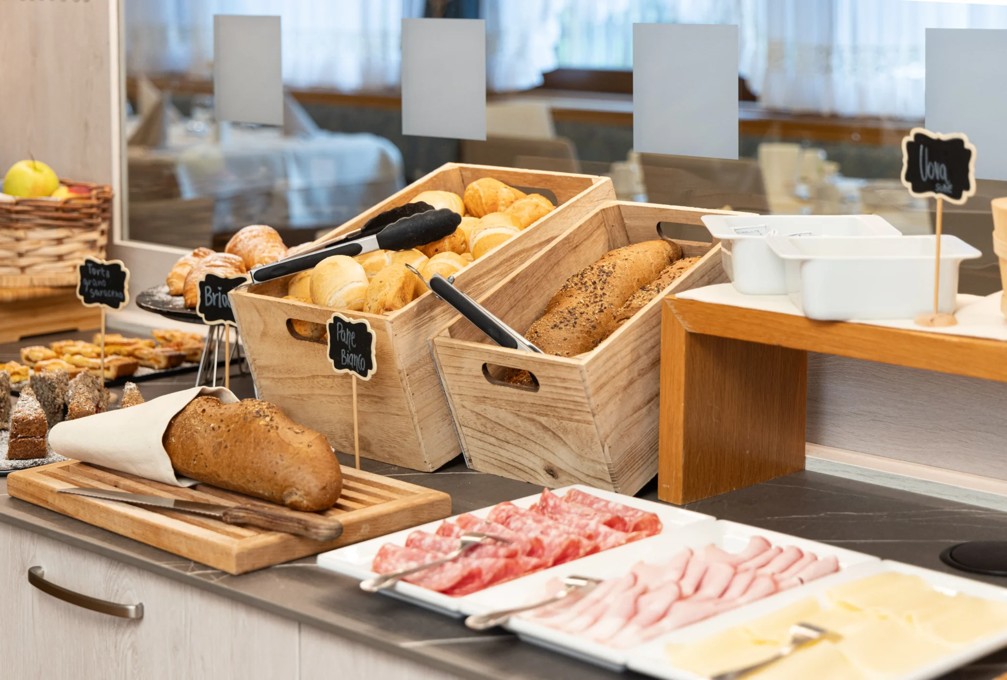Buffet di colazione con assortimento di pane, salumi e formaggi.
