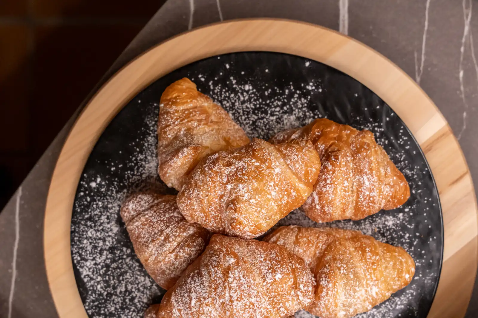 Un piatto di croissant spolverati di zucchero a velo.