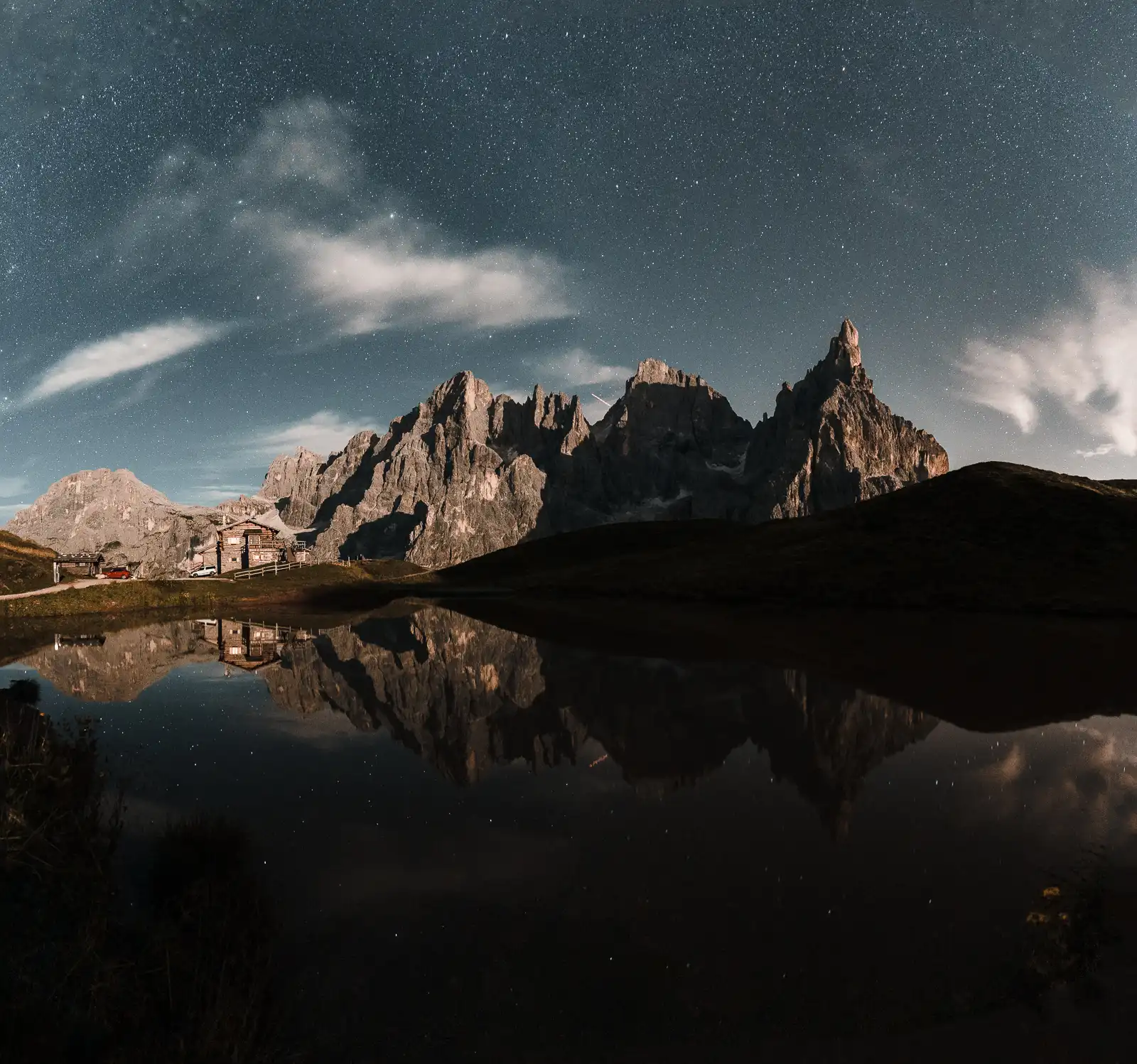 Montagne riflesse in un lago sotto un cielo stellato.