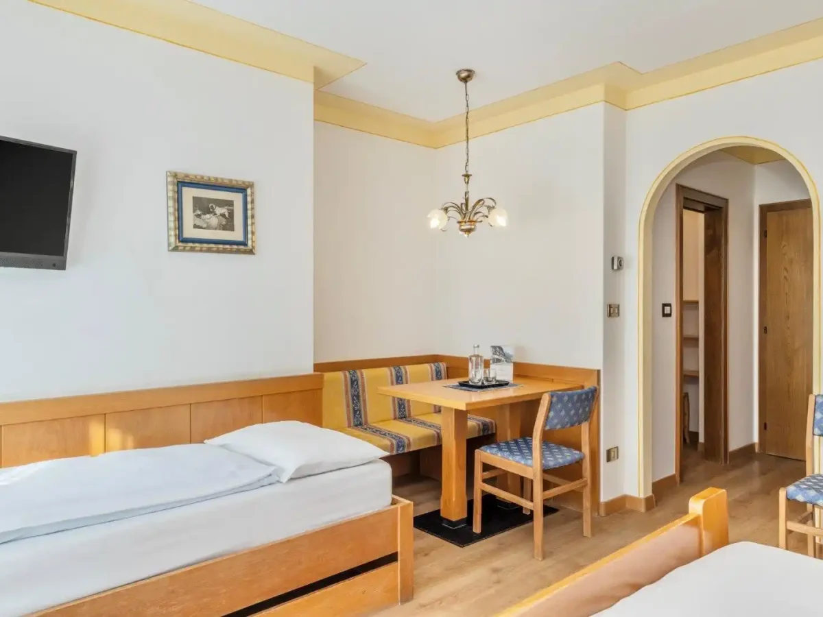 Camera d'albergo accogliente con letto singolo, angolo salotto e televisione.
