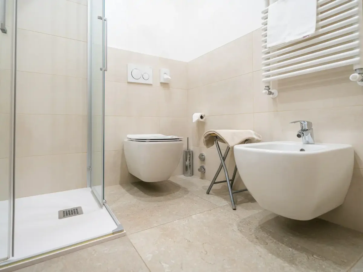 Bagno moderno con doccia, wc e bidet su piastrelle beige.