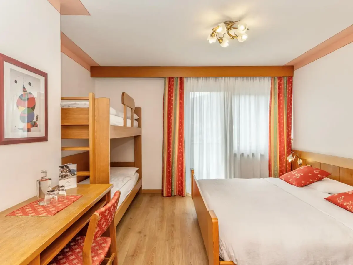 Camera con letto matrimoniale, letto a castello e scrivania in legno.