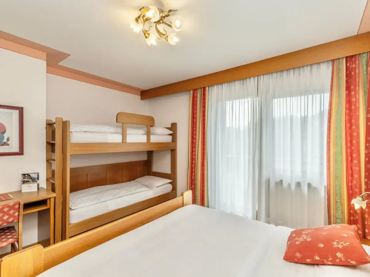 Camera da letto accogliente con letti a castello e finestra con tende colorate.