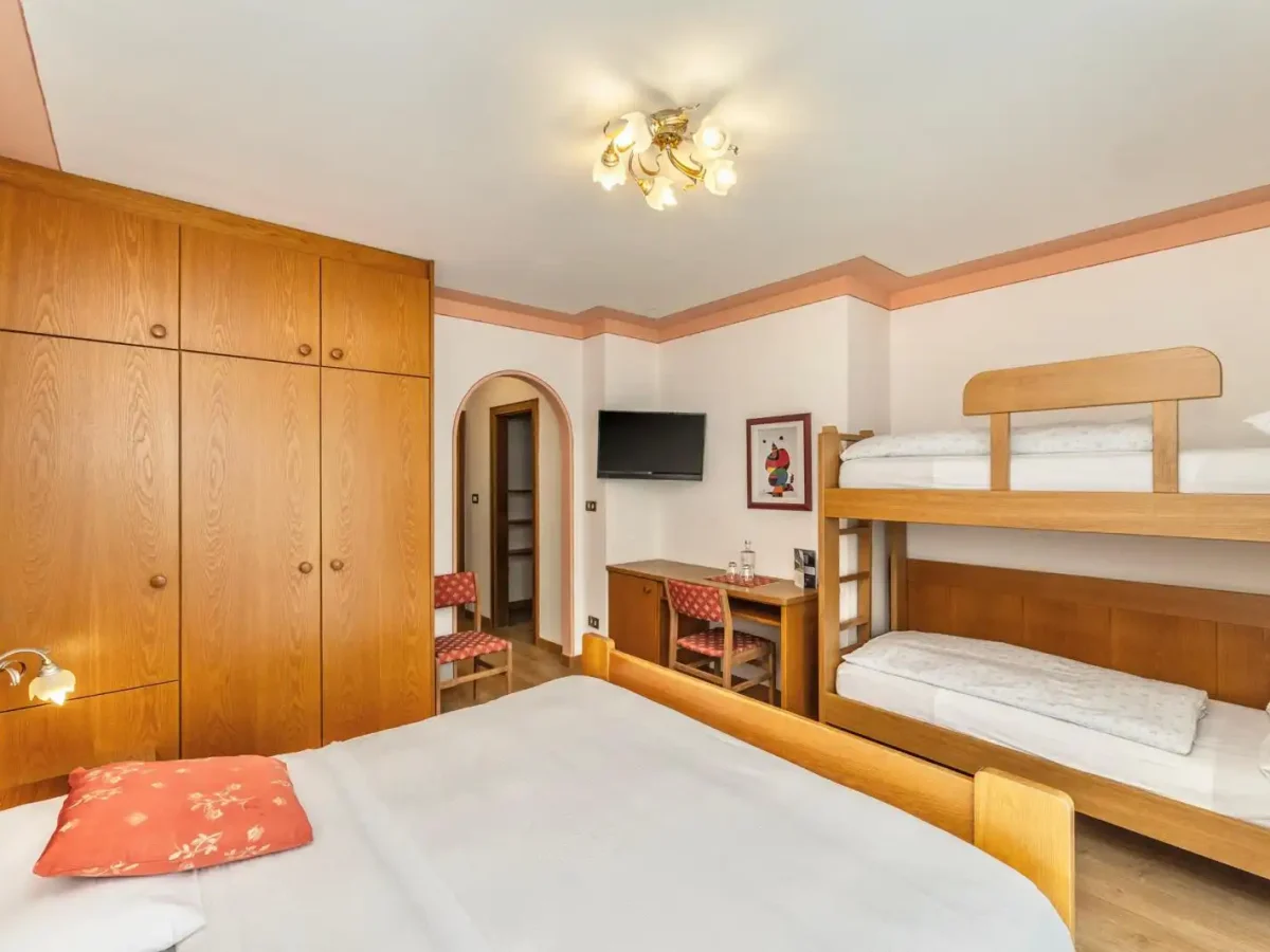 Stanza d'albergo accogliente con letto matrimoniale, letto a castello e arredamento in legno.