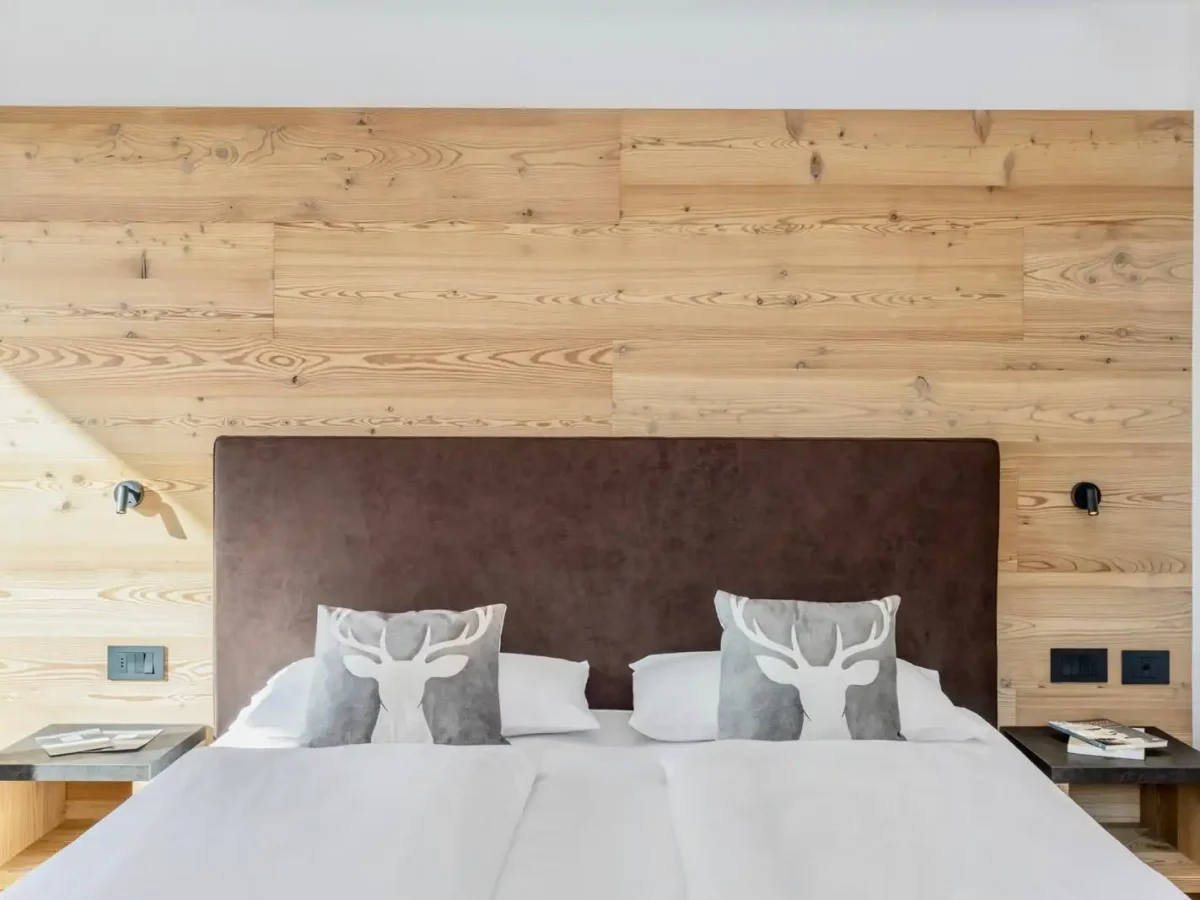 Letto matrimoniale con testiera in legno e cuscini decorati con motivo di cervo.