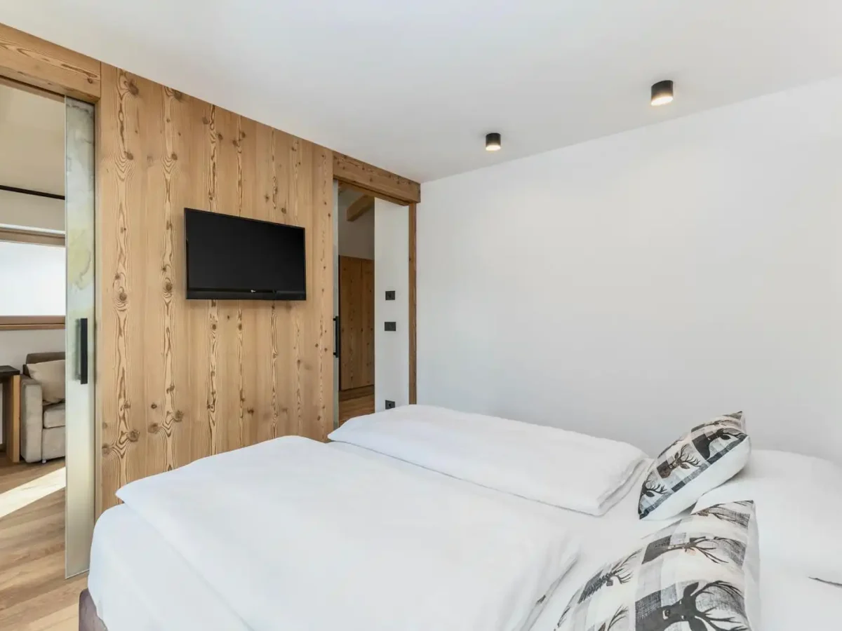Camera da letto moderna con pareti in legno, letto matrimoniale e TV a schermo piatto.