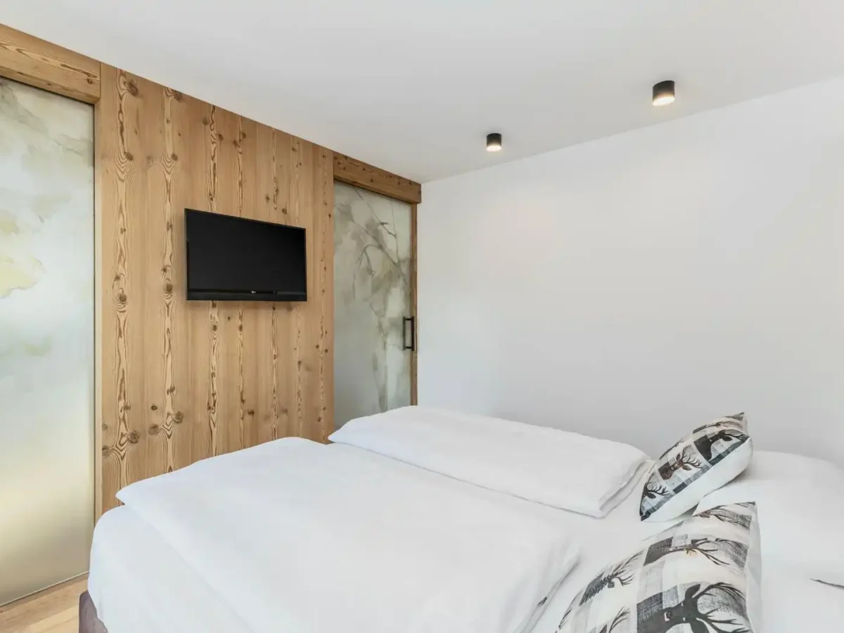 Camera da letto moderna con letto matrimoniale, televisione a parete e decorazioni in legno.