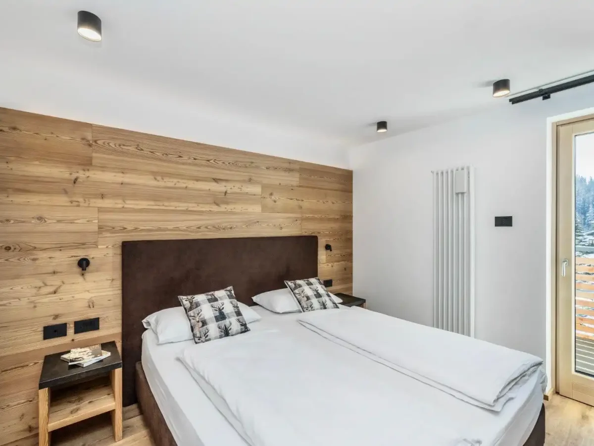 Camera da letto moderna con pareti in legno, letto matrimoniale e balcone esterno.