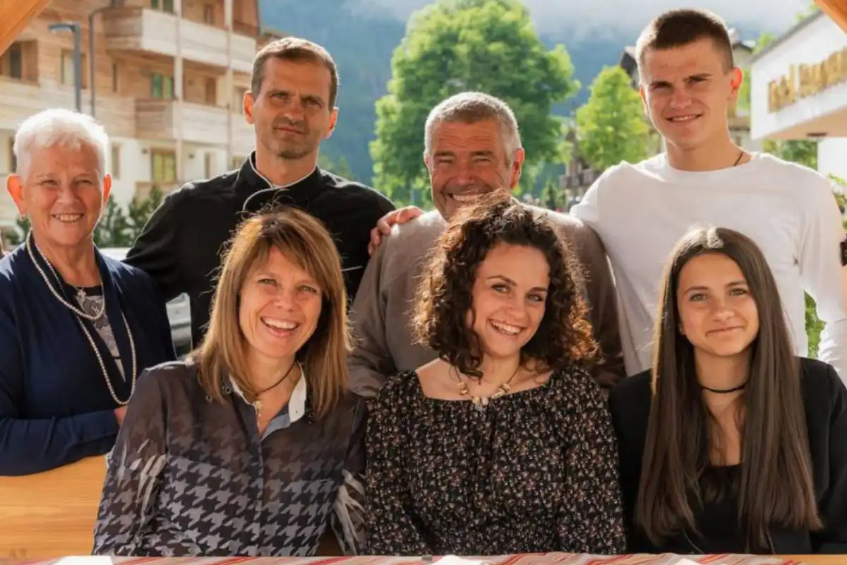 Un gruppo di sette persone sorridenti riunite all'aperto, in un ambiente montano.
