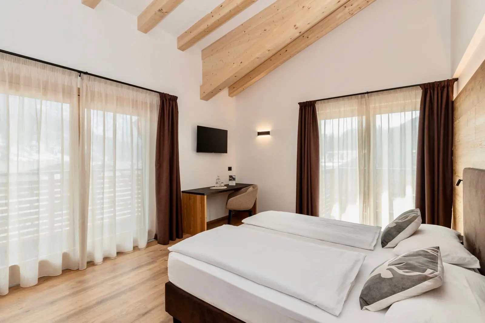 Camera d'albergo moderna con letto matrimoniale, scrivania e ampie finestre.