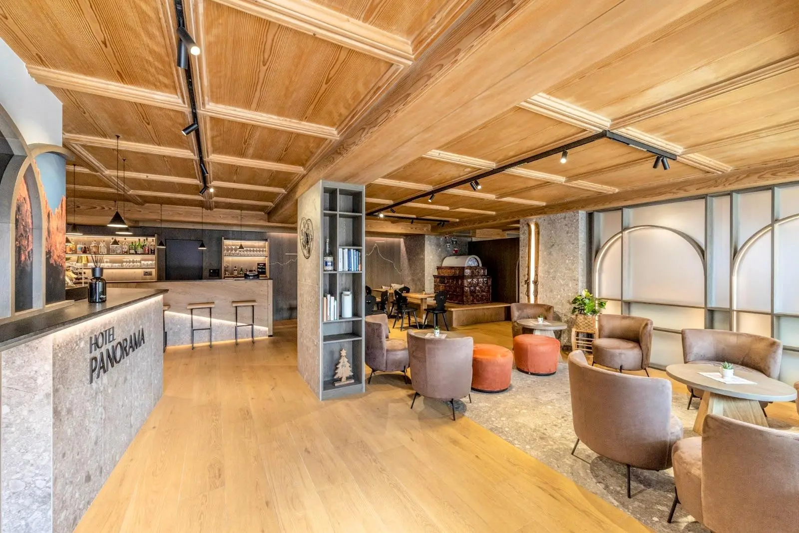 Lobby di un hotel con arredi moderni, pavimento in legno e area bar accogliente.